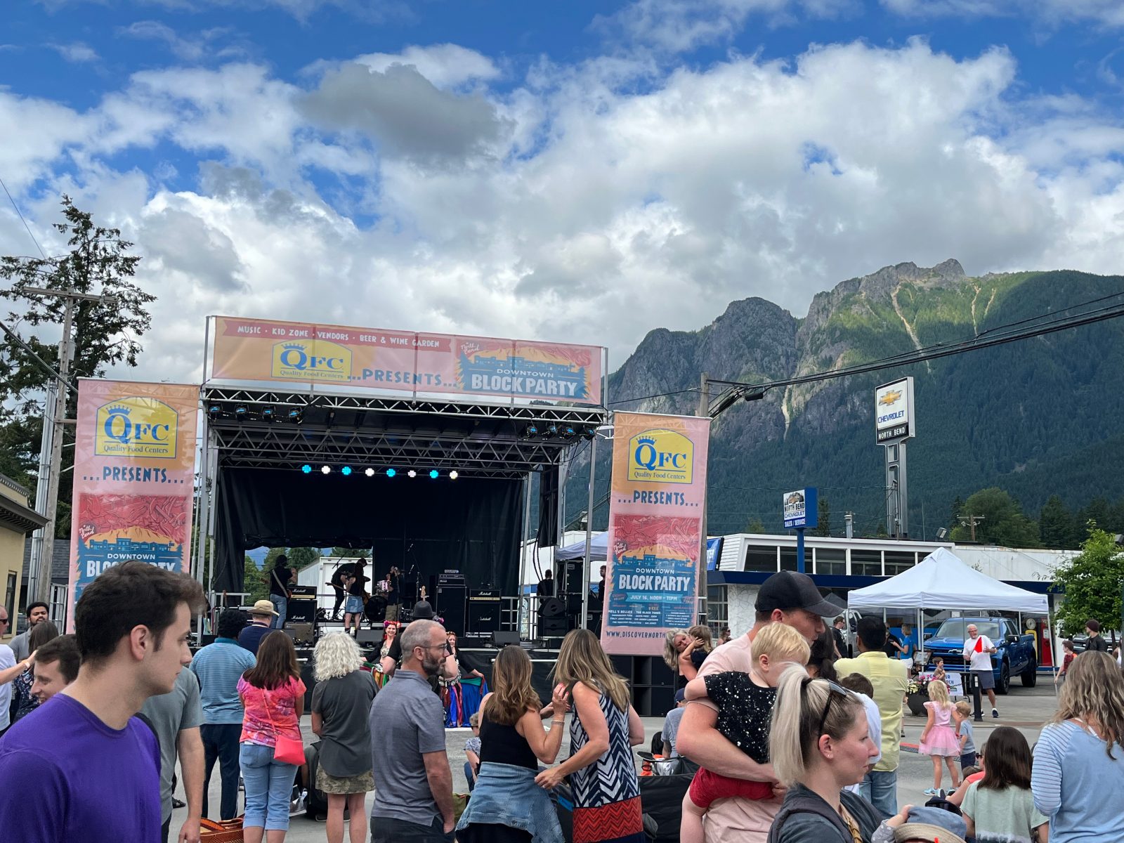 Block-party crowd in front of a banner-wrapped mobile stage