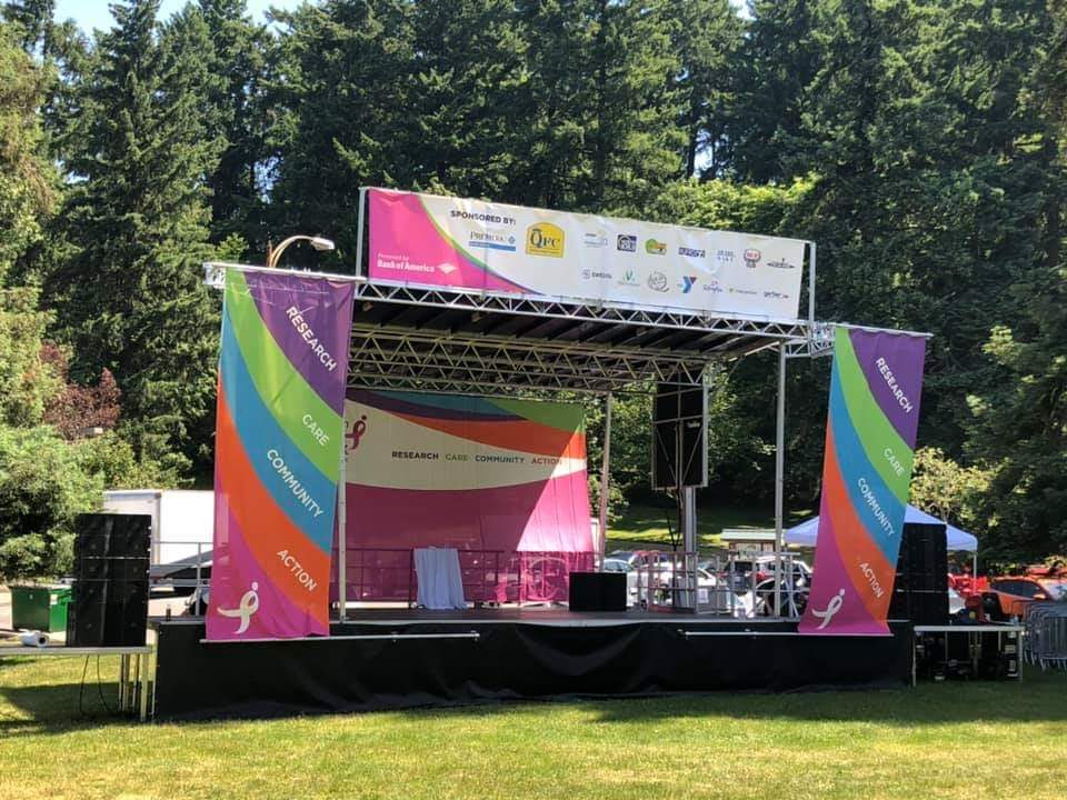 Mobile stage with sponsor banners set up on a park lawn